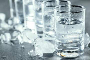 Cold vodka in shot glasses on a black background.
