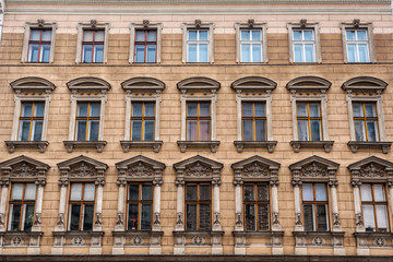 Fototapeta na wymiar Vienna, Austria - December 27, 2017. Old european windows with molding and bas-reliefs on historic building facade.