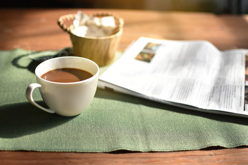 Cup of coffee and newspaper on the table ,shop background,morning,defocus