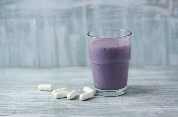 Glass of Protein Shake with milk and blueberries and BCAA amino acids in background. Sport nutrition. Rustic wooden background. Copy space. 