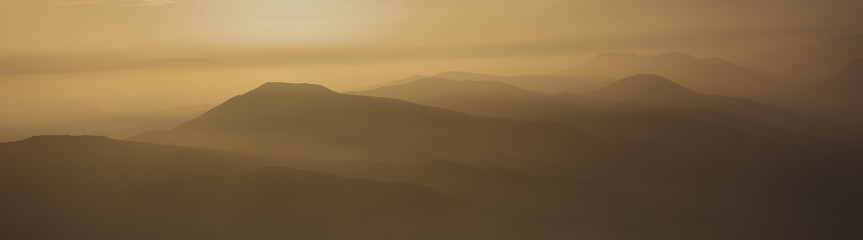 Fototapeta na wymiar Layered mountains in warm light of sunset
