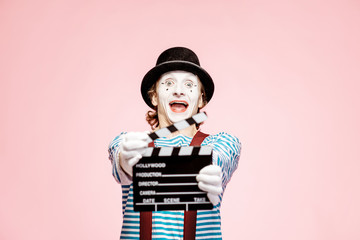 Portrait of an actor as a pantomime with cinematography clapperboard on the pink background