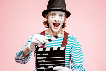 Portrait of an actor as a pantomime with cinematography clapperboard on the pink background