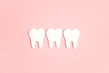 White paper teeth on pink background. Dental health concept. Flat lay, top view, copy space for text.