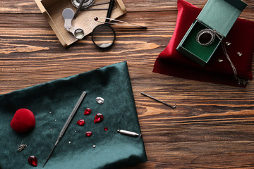 Precious stones and jeweler's tools on wooden table