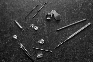 Precious stones and jeweler's tools on grey background