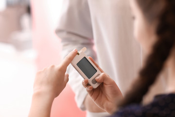 Diabetic girl with digital glucometer in clinic