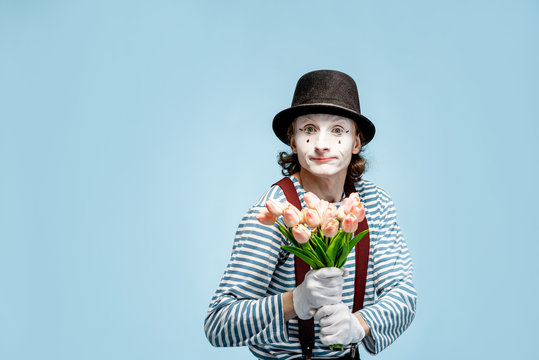 Emotional pantomime posing with tulip bouquet on the blue background indoors. Valentine's Day and love concept