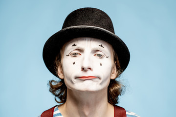 Close-up portrait of an actor as a pantomime with white facial makeup showing expressive emotions...
