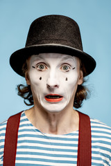 Close-up portrait of an actor as a pantomime with white facial makeup showing expressive emotions...