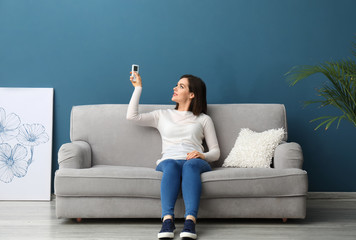 Young woman switching on air conditioner at home