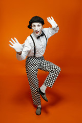 Full length portrait of an actor as a pantomime with white facial makeup showing expressive...