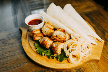 Shish kebab with onion and lavash. Food photo. Restaurant dishes on the wooden table.