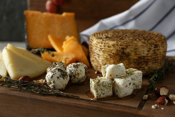 Assortment of tasty cheese on wooden board, closeup