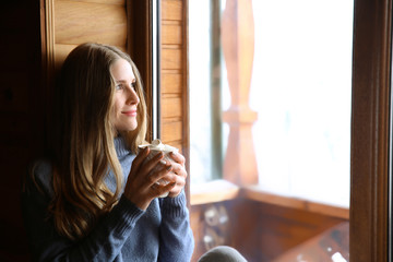 Woman drinking hot cacao near window in morning