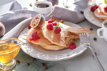 Tasty pancakes with passion fruit and berries on table