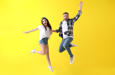 Jumping young couple on color background