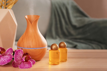 Aroma oil diffuser with bottles on table in room