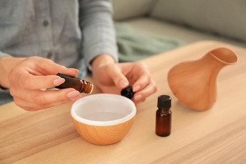 Woman filling essential oil diffuser, closeup