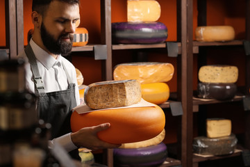 Male seller with delicious cheese in store