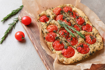 Wooden board with tasty Italian focaccia on grey table