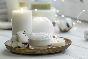 Beautiful burning candles with jar of cream on windowsill