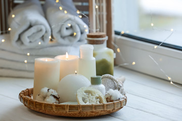 Beautiful burning candles with cosmetic products on windowsill