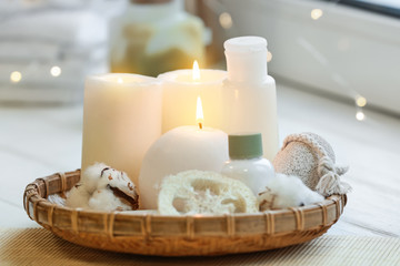 Beautiful burning candles with cosmetic products on windowsill