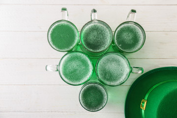Glassware with green beer for St. Patrick's Day on wooden table