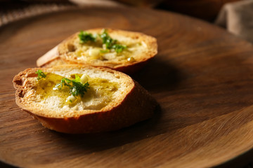 Sliced bread with olive oil, garlic and herbs on wooden plate