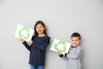 Children holding paper sheets with recycling symbol on white background