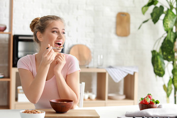 Young woman eating tasty yogurt at home