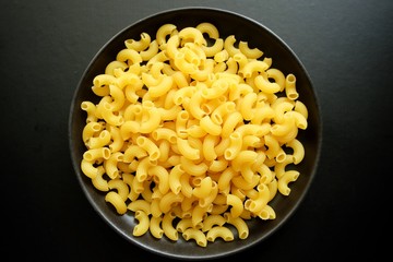 Macaroni on black bowl and black background. 