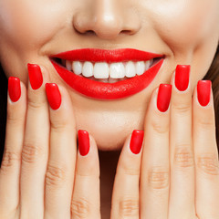 Naklejka premium Smiling woman showing her hand with manicured nails. Red sexy nail polish and makeup lips with bright red color tint lipstick