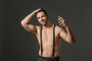 Obraz premium Handsome man with bottle of perfume on dark background