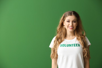 Young female volunteer on color background