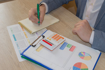 Man, taking notes, calculator on the table. Success, motivation, financial flows, wealth