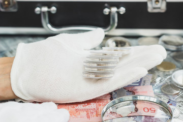 Hands in the white gloves hold different banknotes