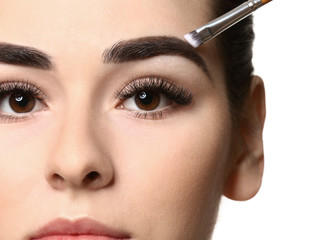 Obraz premium Young woman undergoing eyebrow correction procedure on white background, closeup