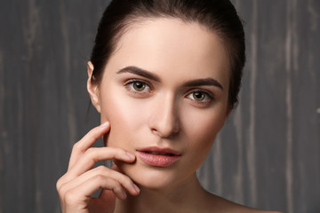 Young woman with beautiful eyebrows on grey background