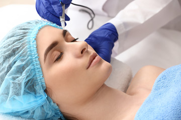 Obraz na płótnie Canvas Young woman undergoing procedure of eyebrow permanent makeup in beauty salon