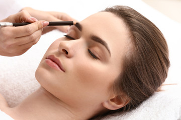 Obraz na płótnie Canvas Young woman undergoing eyebrow correction procedure in beauty salon