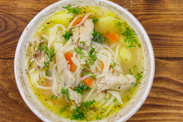 Chicken soup with noodles and vegetables on wooden table. Top view