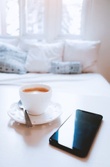 Mobile phone with coffee on a table in bed room
