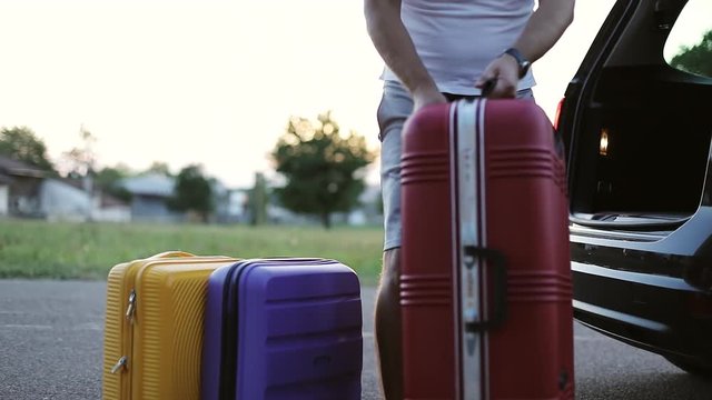 A man gets out of the trunk suitcases. Summer holidays.