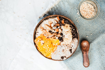 Healthy oatmeal bowl with fruits, nuts and chocolate chips. Breakfast idea, top view flat lay