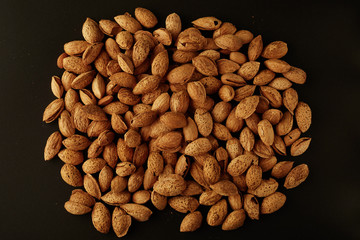 Top view of handful of pecans, almonds on a black background