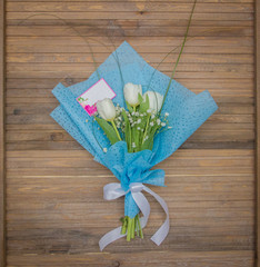 Bouquet of three beautiful white tulips with mockup note on wooden background