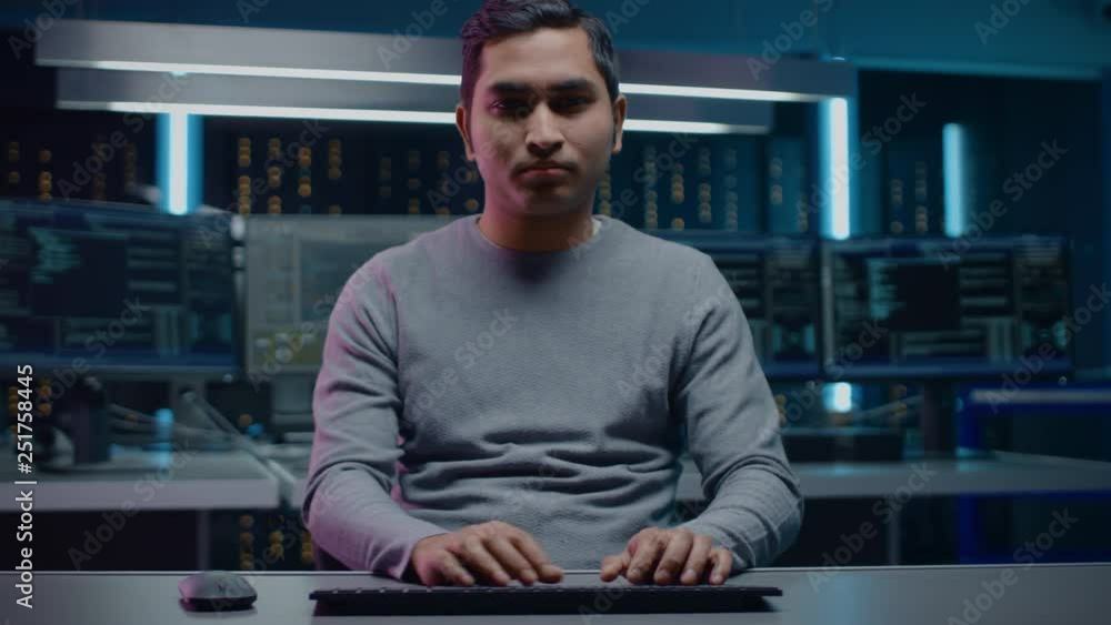 Poster Portrait of Indian Software Developer Sitting at His Desk and Working on Computer in Digital Identity Cyber Security Data Center. Hacking or Programming. POV Camera Shot