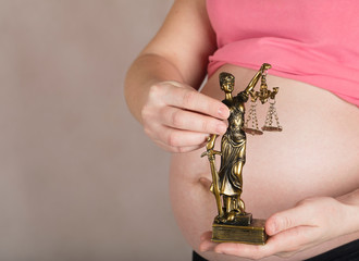 Young pregnant woman keeps statue of Themis.